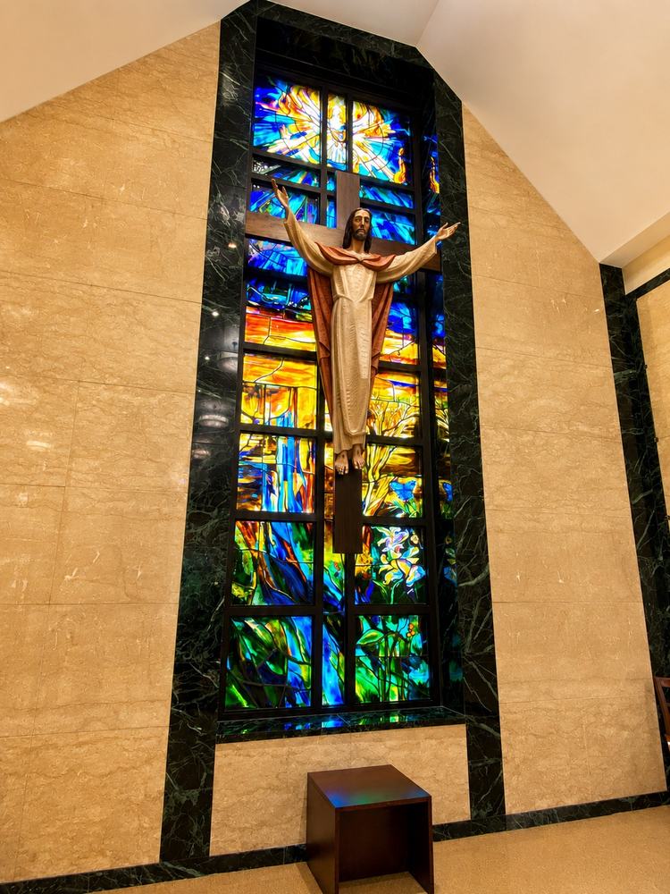 Sculptural crucifix mounted on a stained glass Pentecost window, ecclesiastical commission