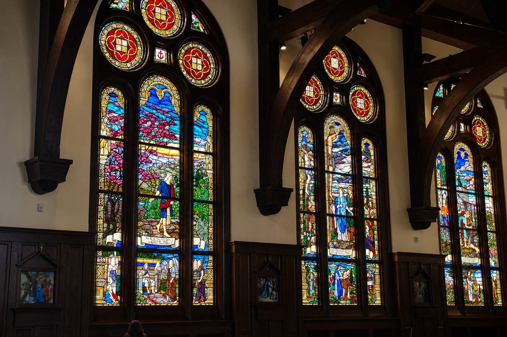 Set of large Gothic arched stained glass windows with narrative religious scenes and rose roundels, church chapel