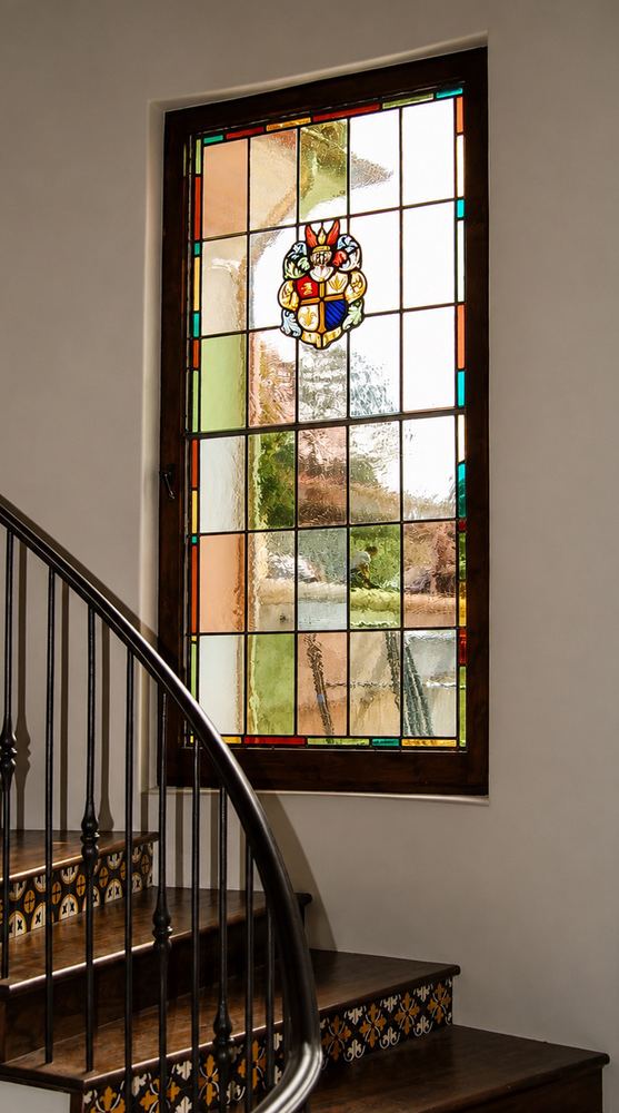 Custom stained glass window with a heraldic crest medallion, staircase installation