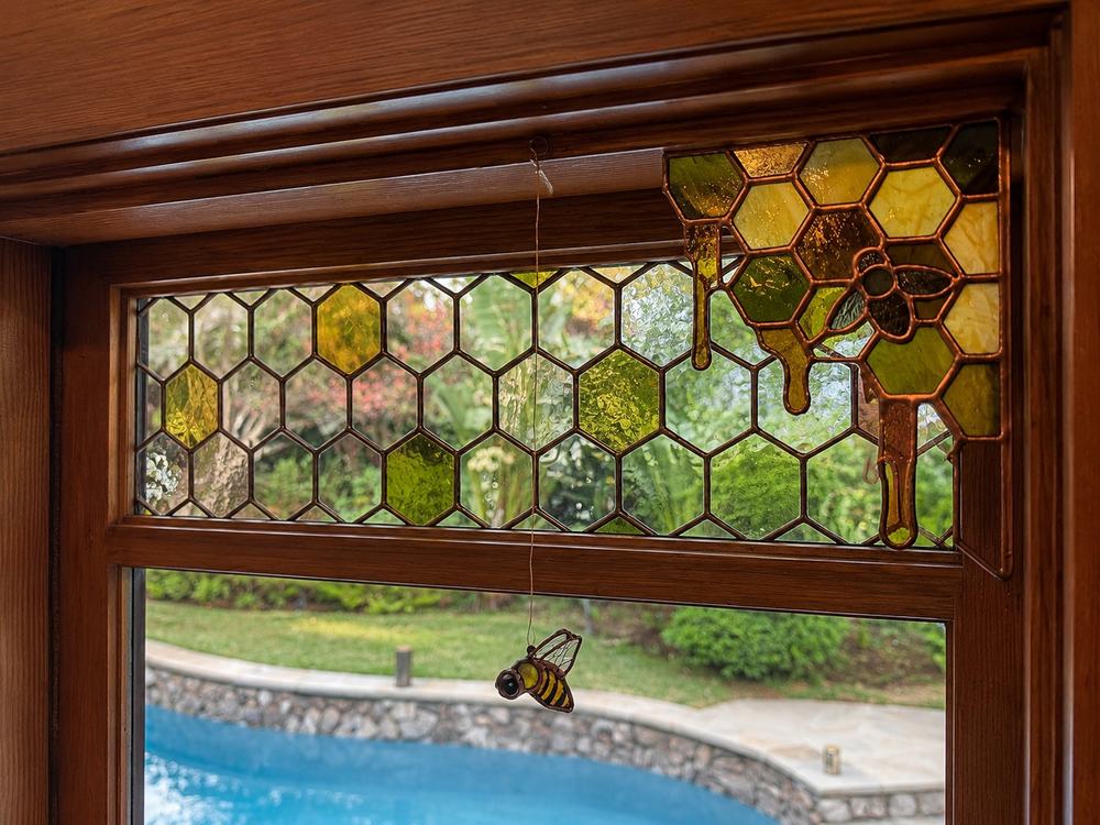 Custom stained glass transom window with honeycomb pattern, dripping honey, and a hanging bee accent
