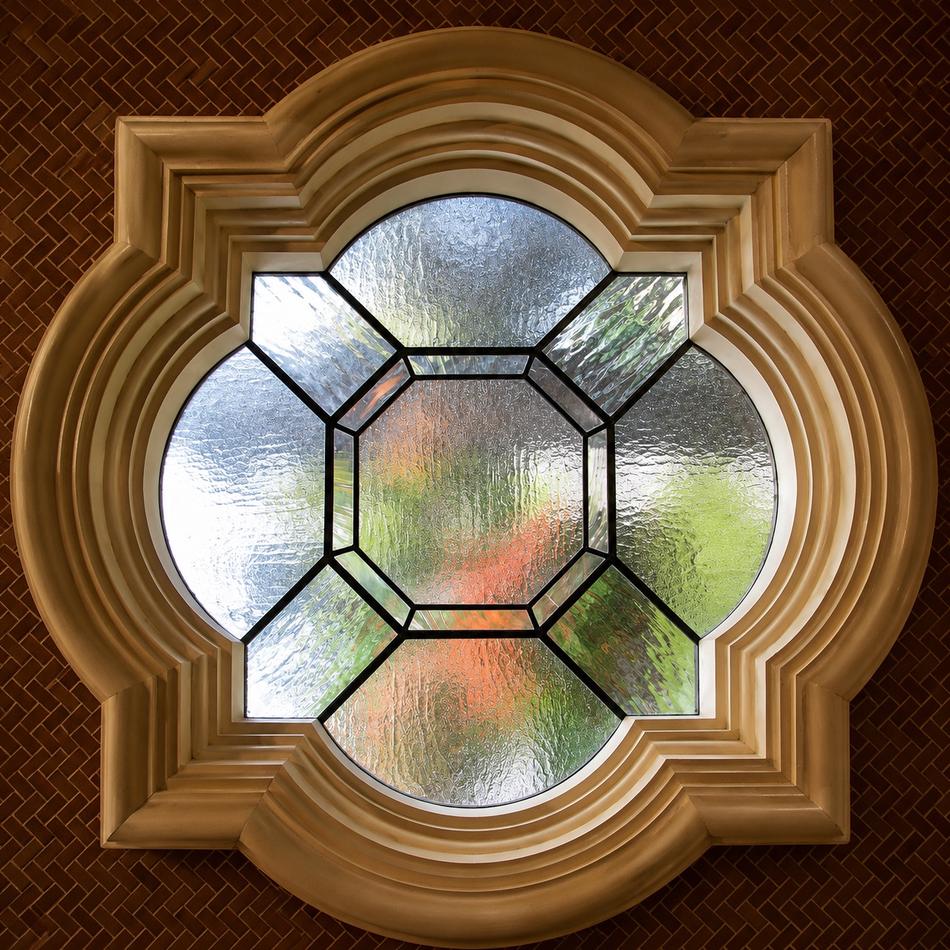 Custom leaded glass quatrefoil window with textured glass panes in an ornate wood surround