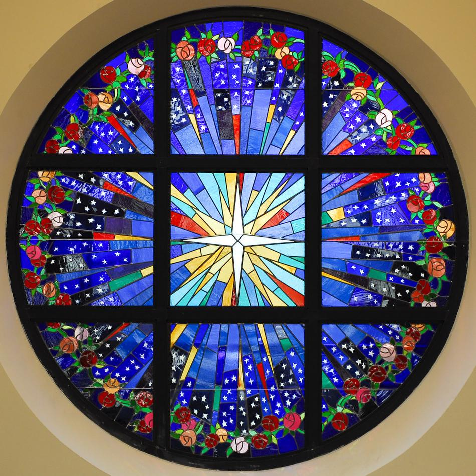 Large round custom stained glass window with a radiant star of Bethlehem and rose vine border